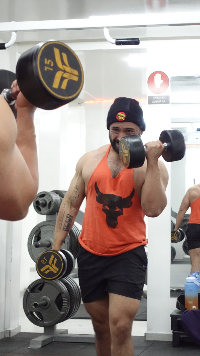 Cliente entrenando bíceps con mancuernas en el gimnasio